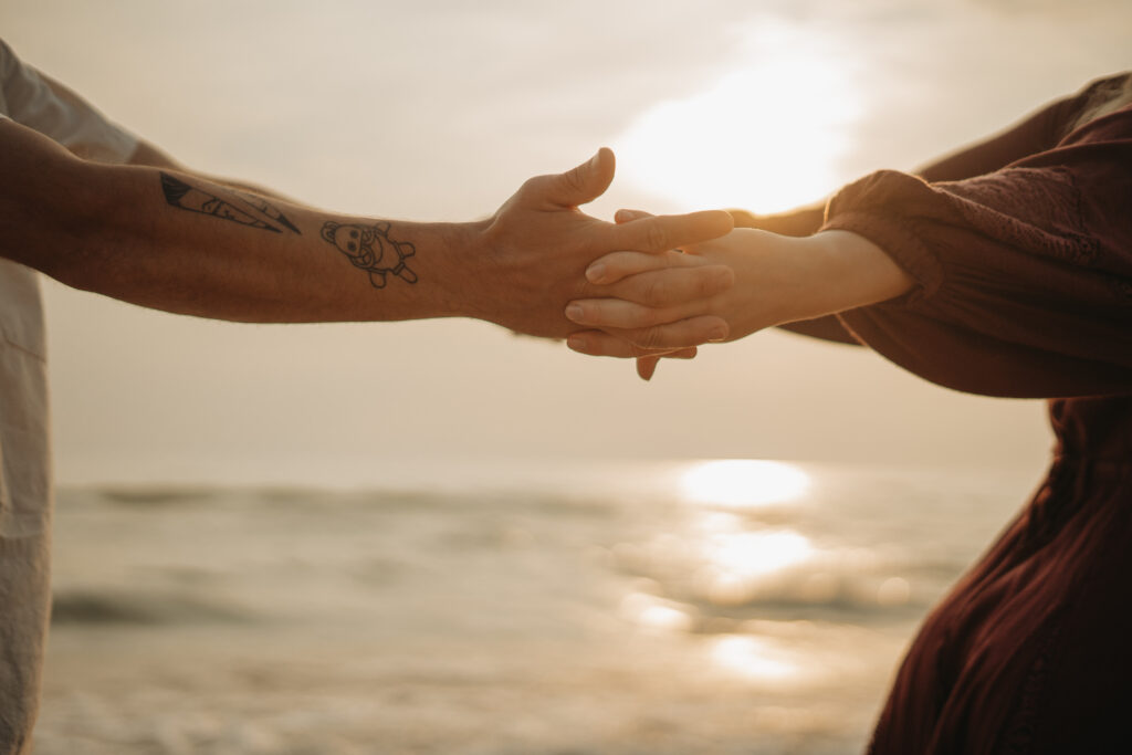 hands are intertwined on the beach on an intimate elopement day. 