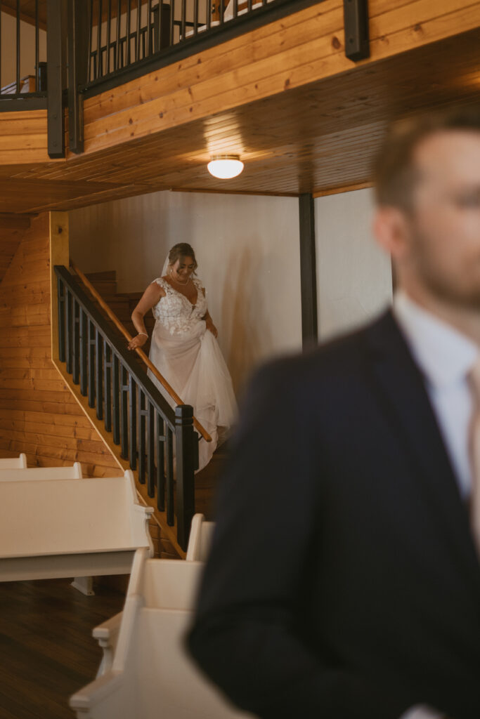 A bride descends the stairs for her first look with her groom at the Chapel at New Richmond in Michigan. 