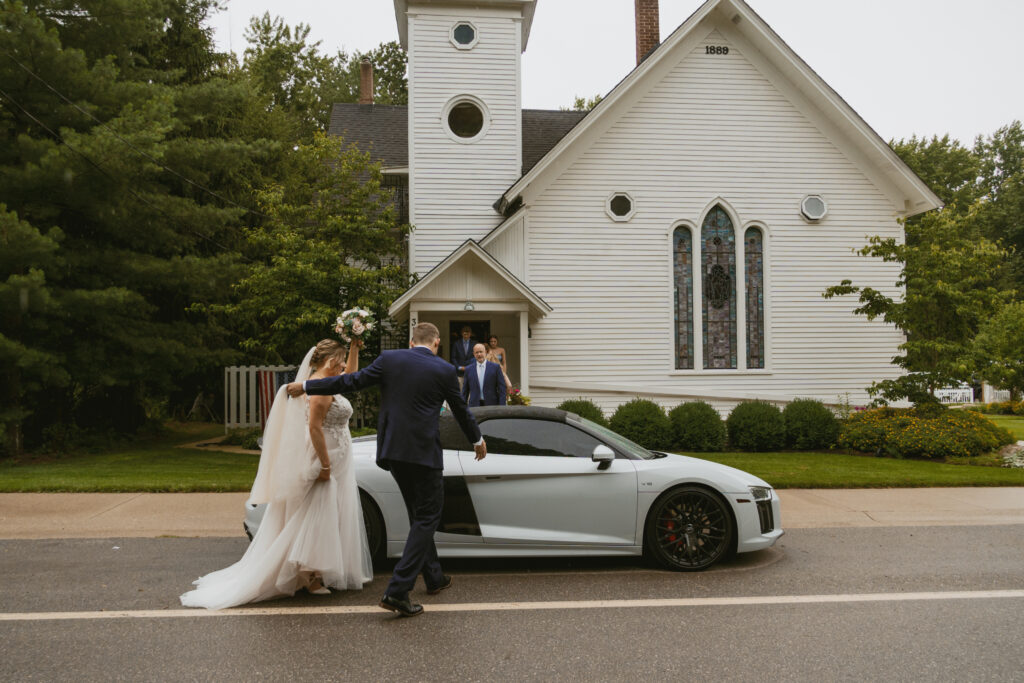 Groom helps his bride into their getaway car. 