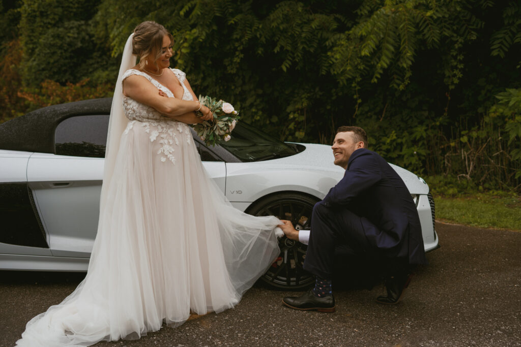 groom cleans the wheel of their getaway car with Bride's dress.