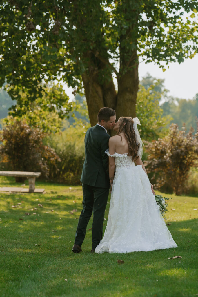 bride and groom kiss beneath a tree