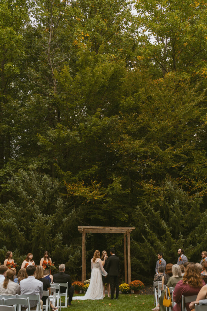 Bride and Groom share vows beneath the pine trees. outdoor wedding in michigan.