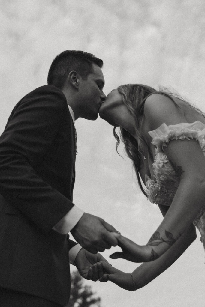 Bride and groom hold hands and kiss