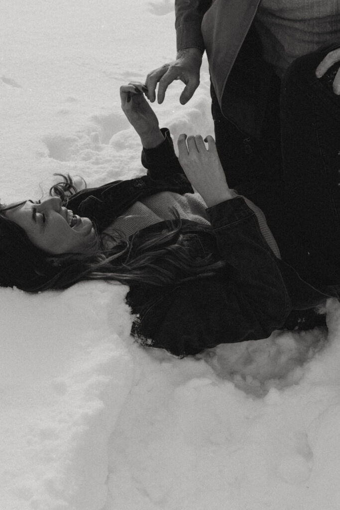 Couple lays in the snow for their engagement photos 