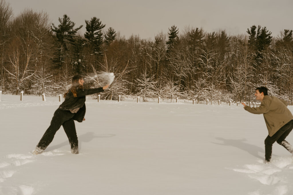 couple has a snow ball fight during their engagement photos 