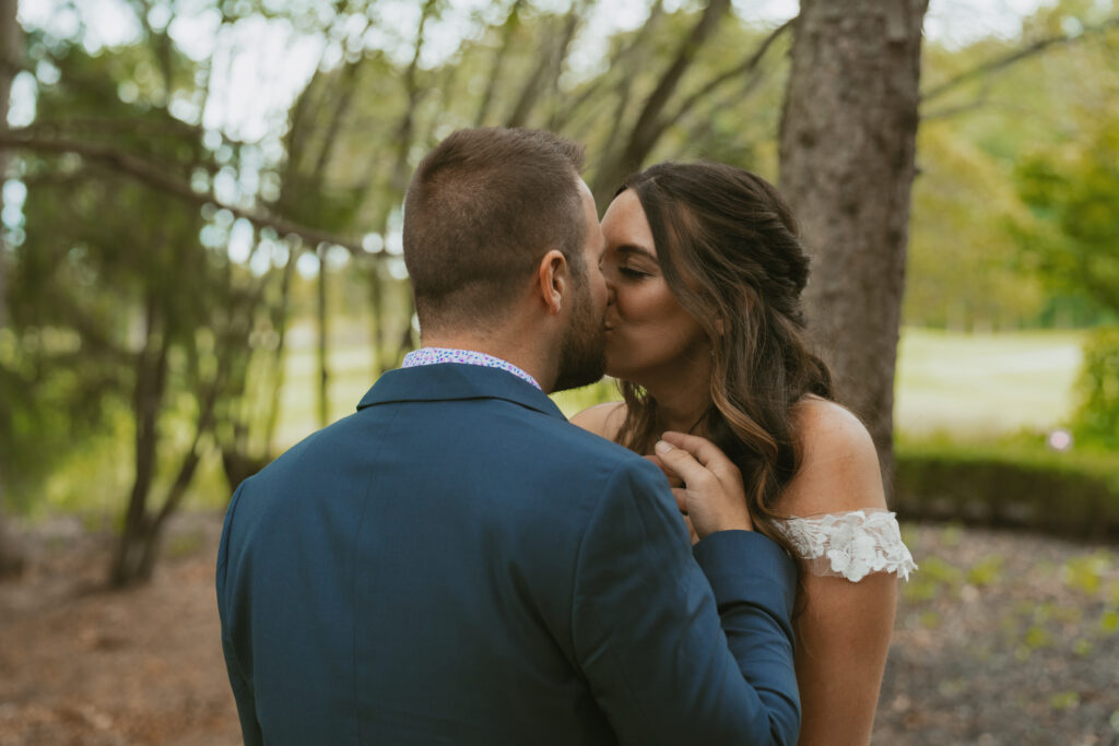 Wedding portrait of a couple sharing a kiss in the forest