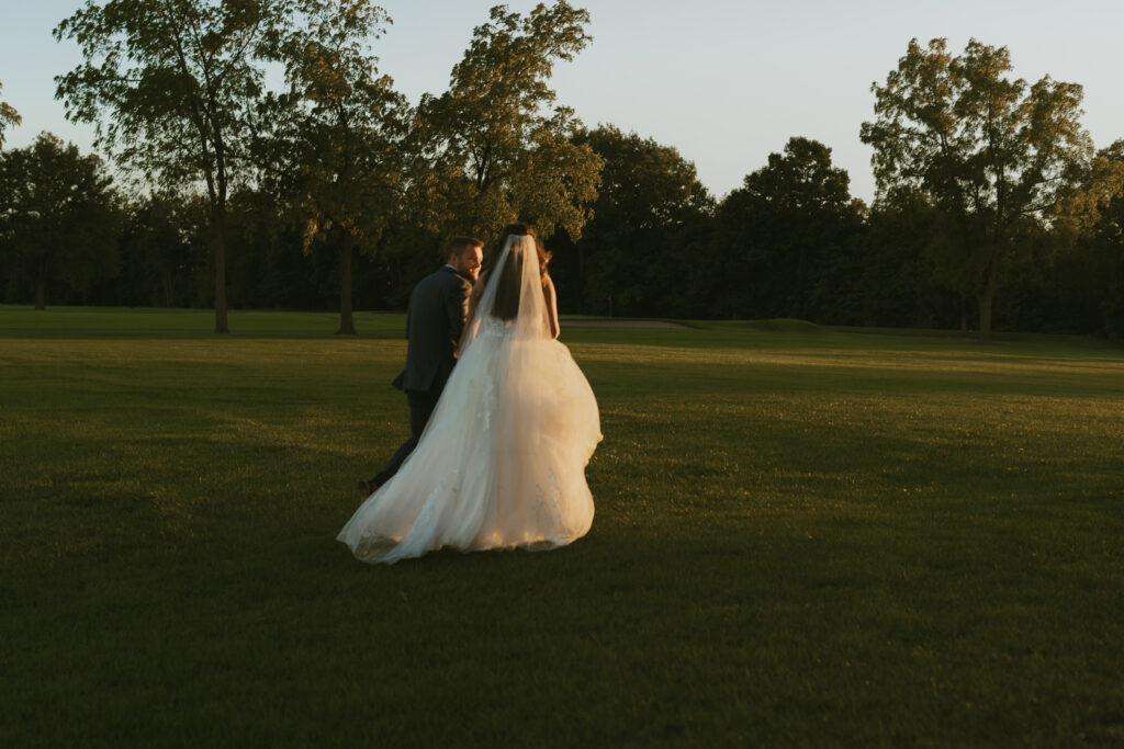 A couple walks together at golden hour on their wedding day