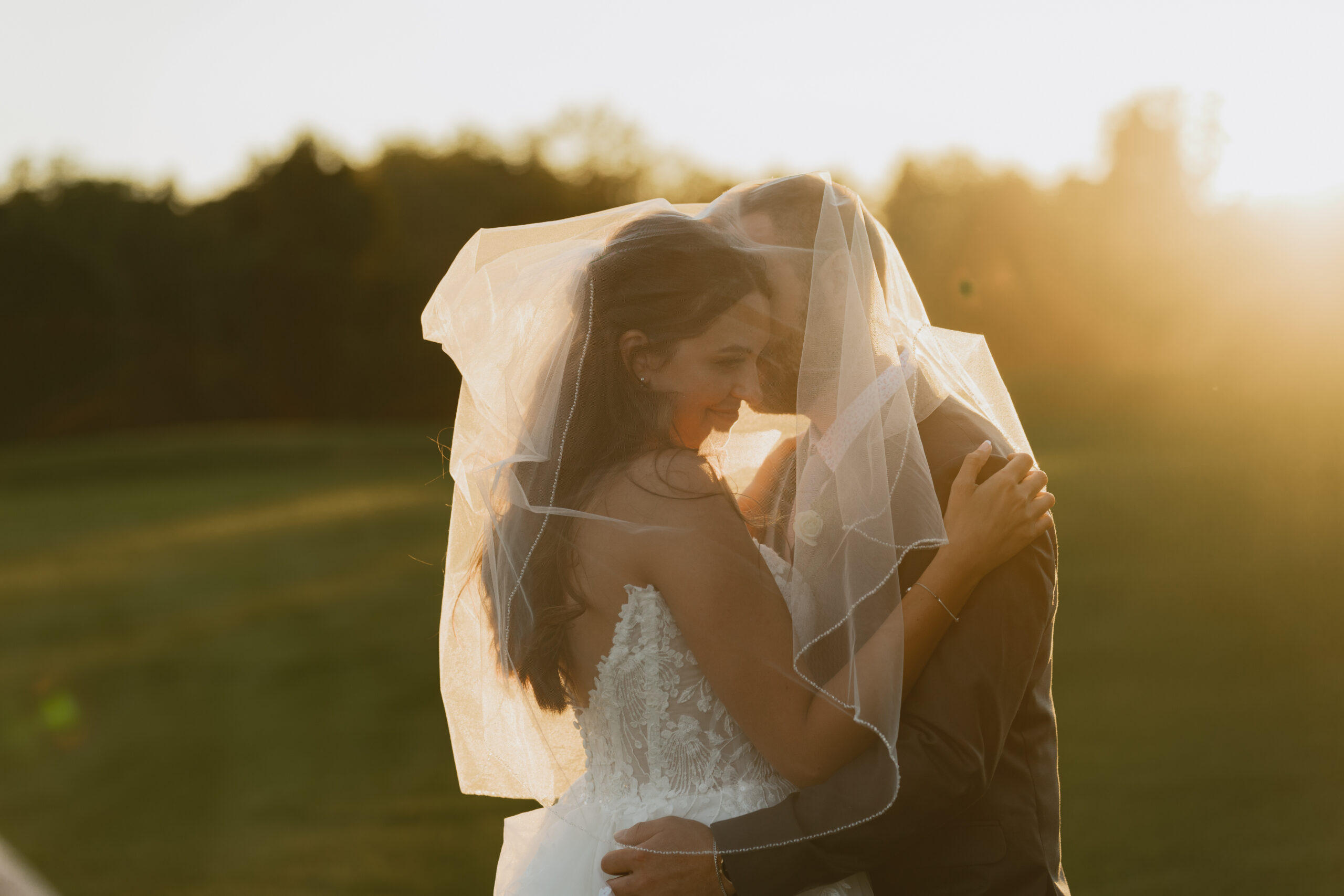 Newly Married couple cuddles beneath their viel