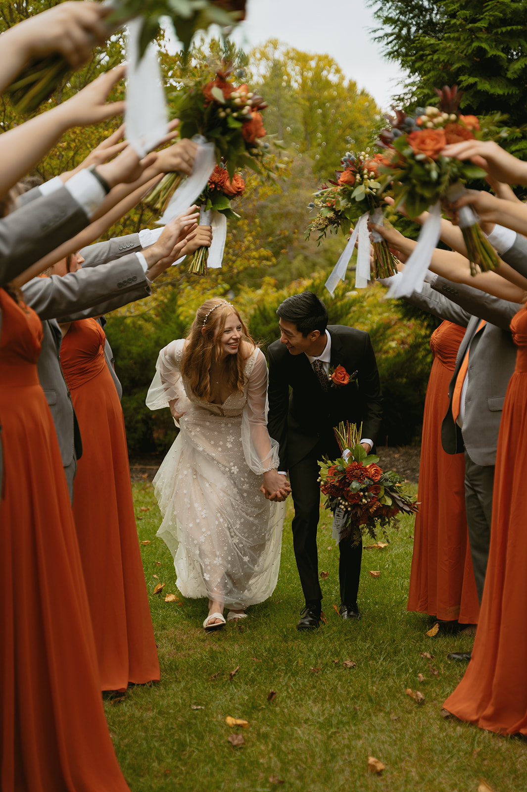 bride and groom walk through an arm tunnel as they leave their micro wedding ceremony