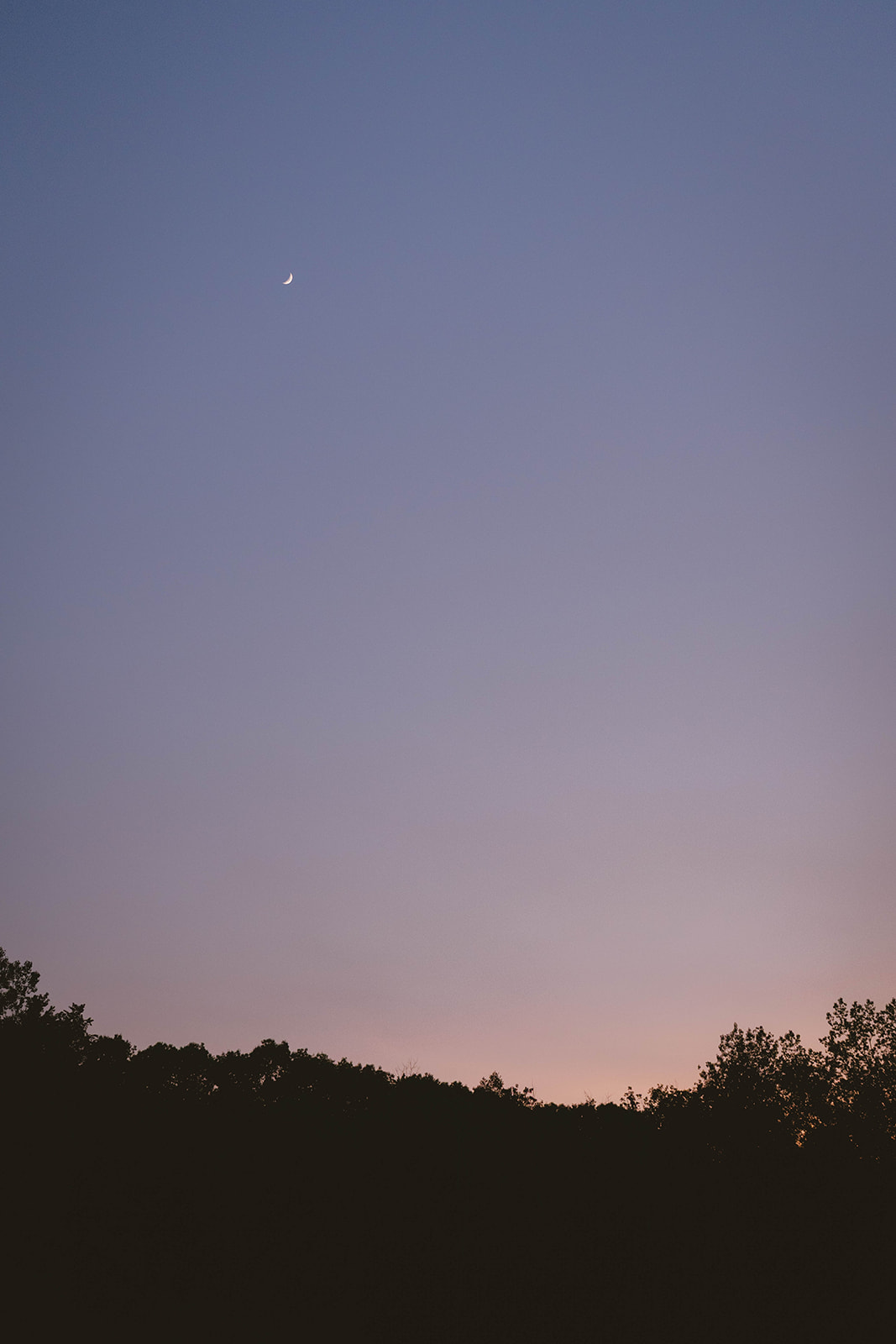 beautiful view of the pink setting sun as the sliver of moon hangs in the sky