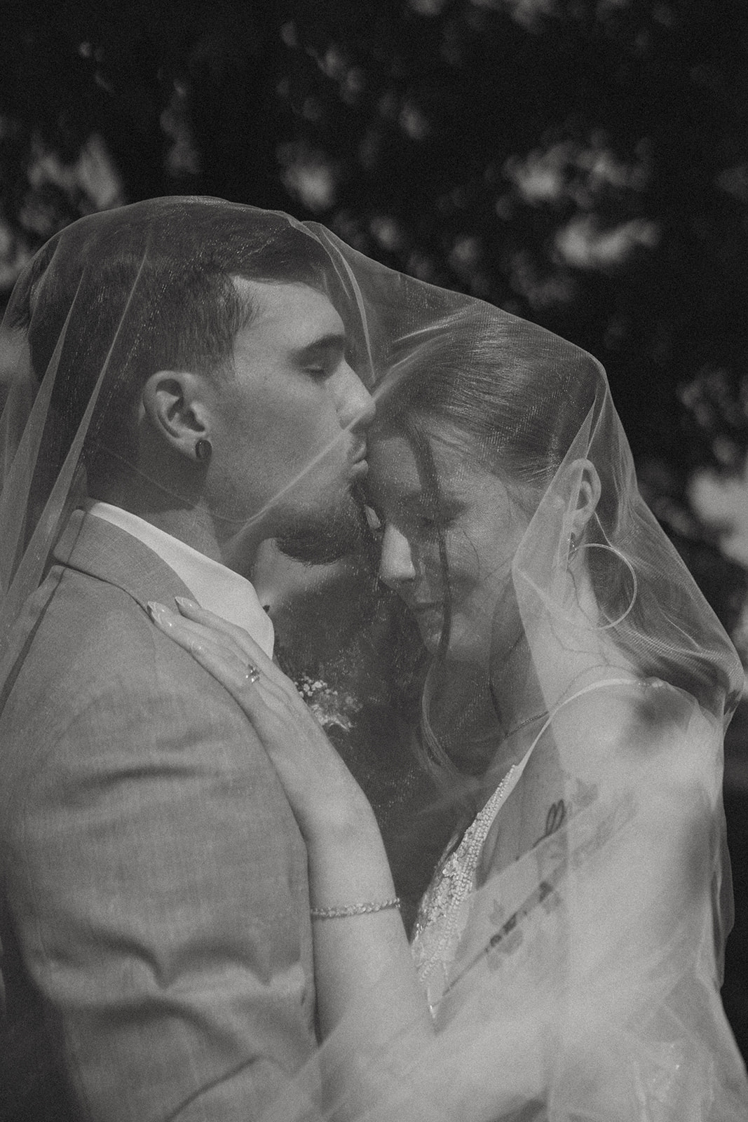 bride and groom share a kiss under the veil 