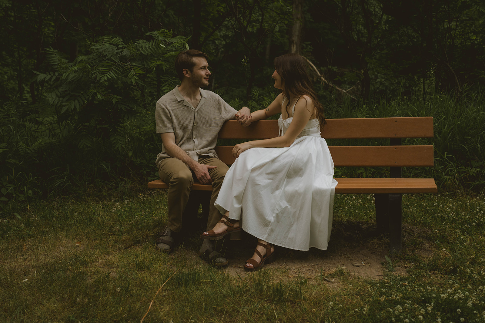 beautiful couple sit on a park bench during their Grand Rapid engagement photoshoot
