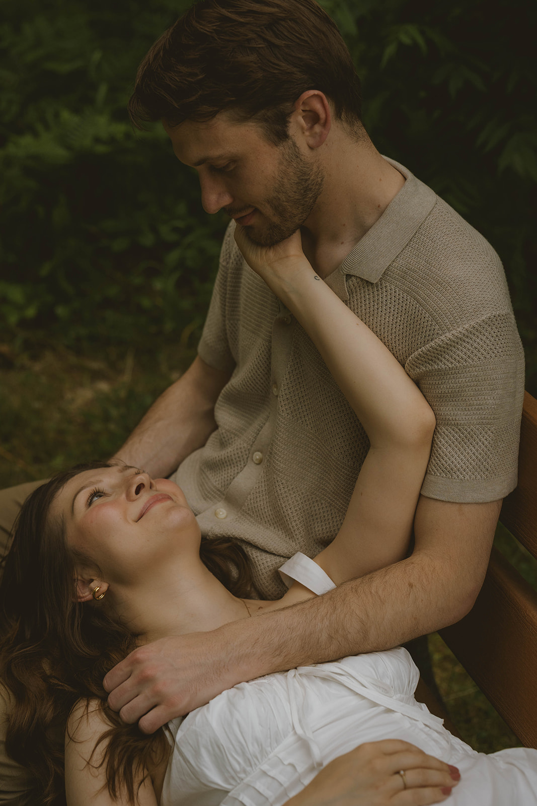 couple pose together on a park bench in Grand Rapids for their engagement session