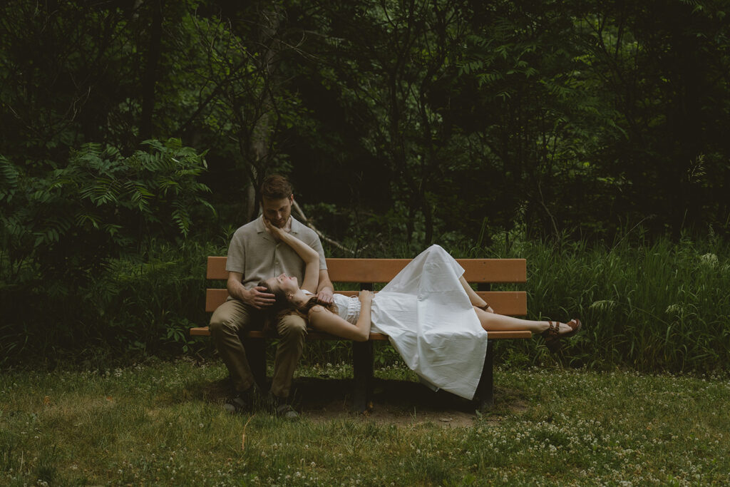 couple pose together on a park bench in Grand Rapids for their engagement session