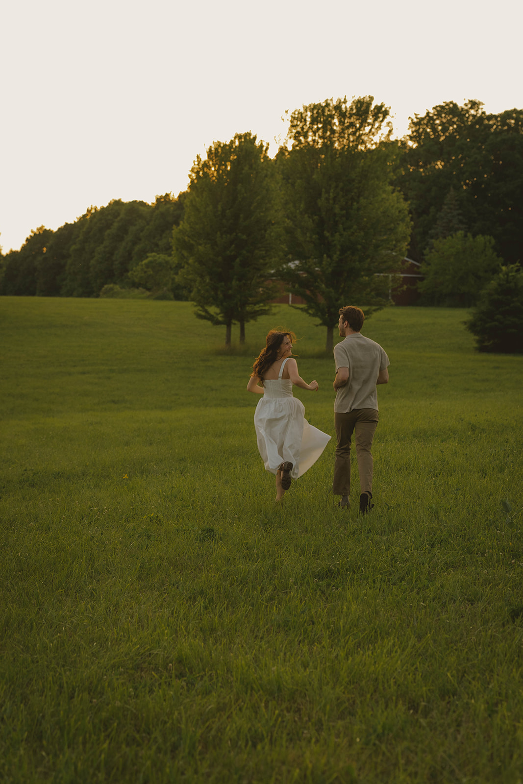 beautiful couple run through a Michigan field at golden hour