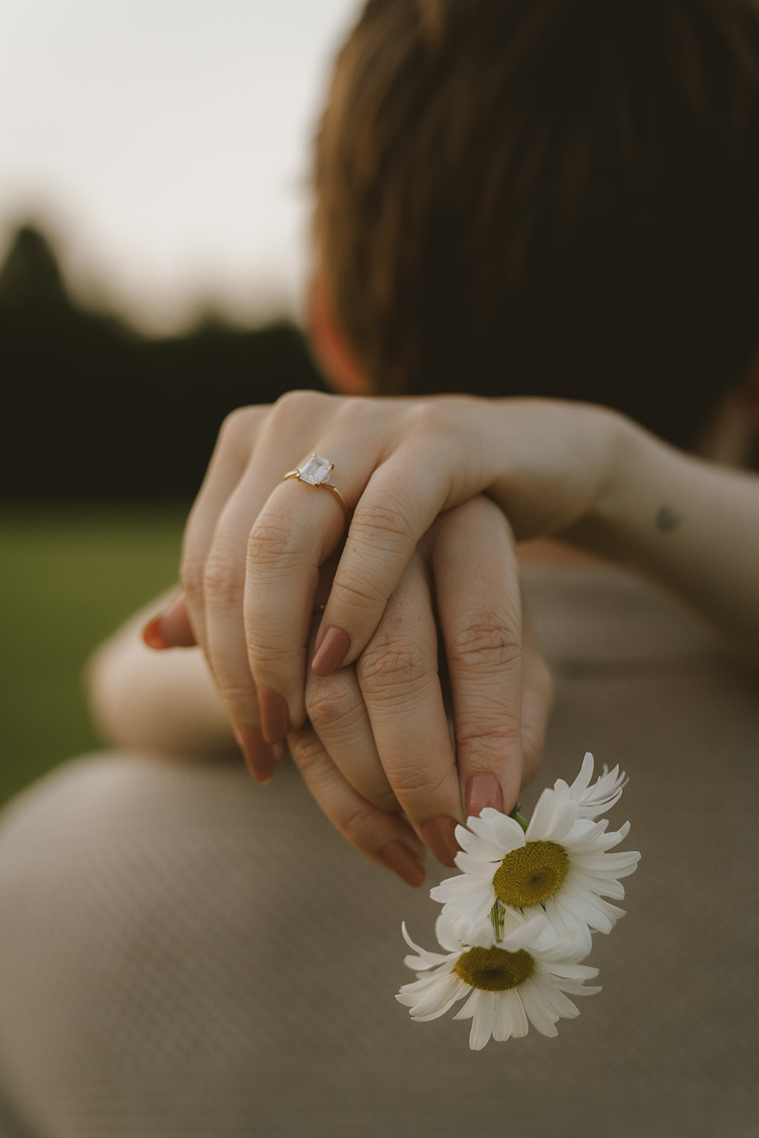future wife holds a flower and shows off her new ring in a stunning detail photo