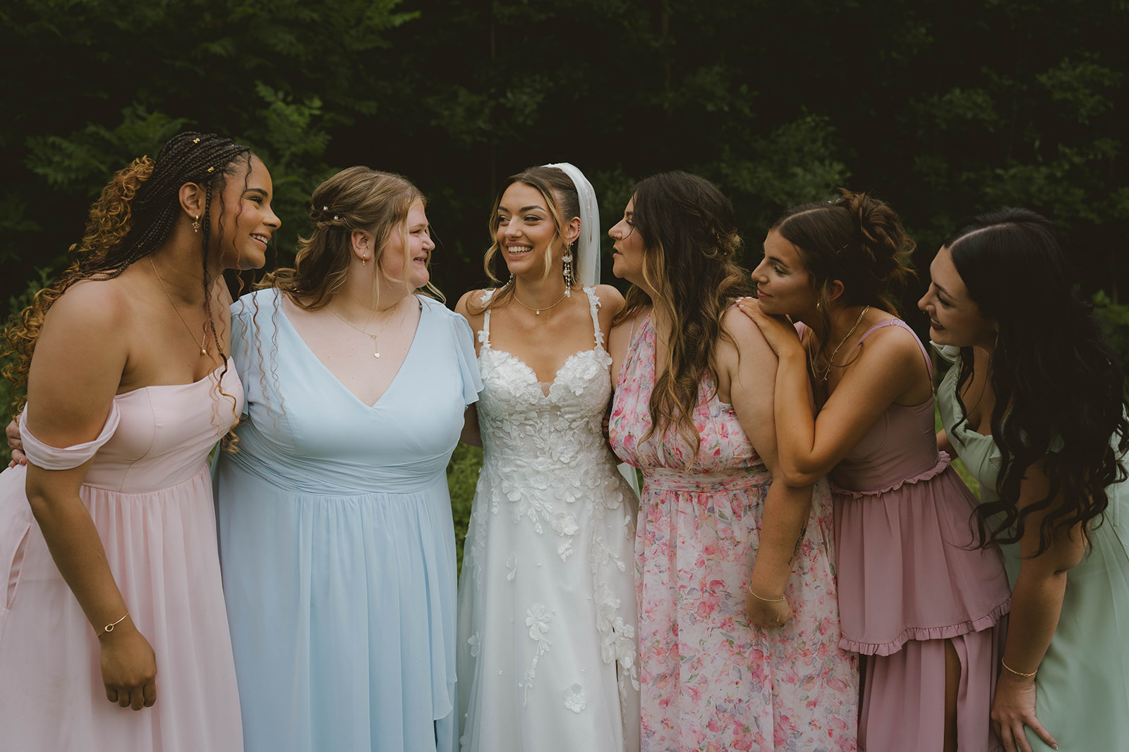 bridesmaids pose with the bride on her stunning outdoor wedding day