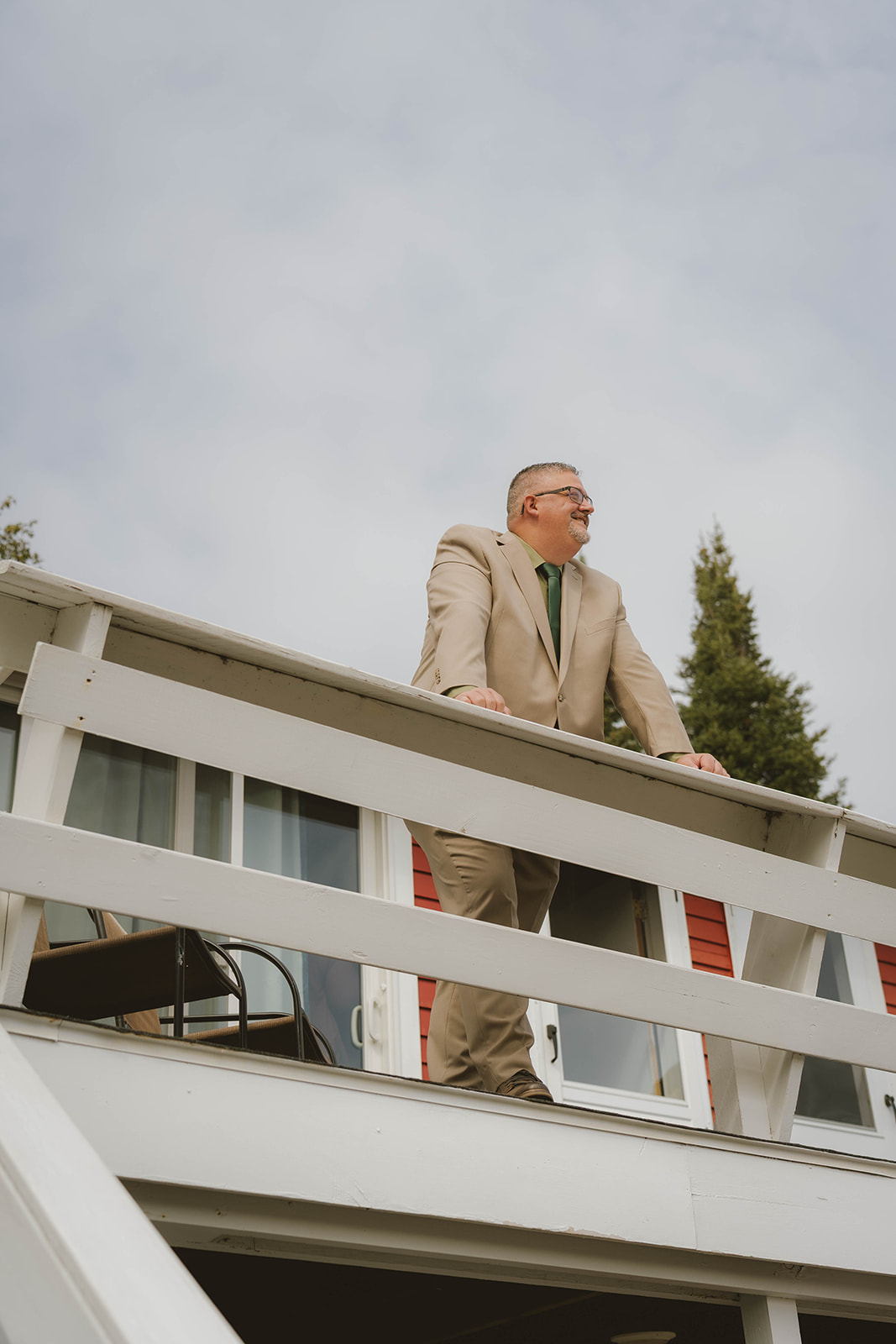 groom stands looking over Copper Harbor off the balcony