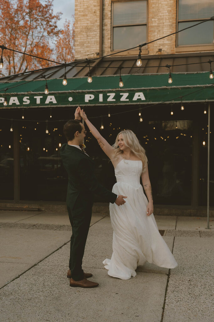 bride and groom share a little dance outside a pizza restaurant