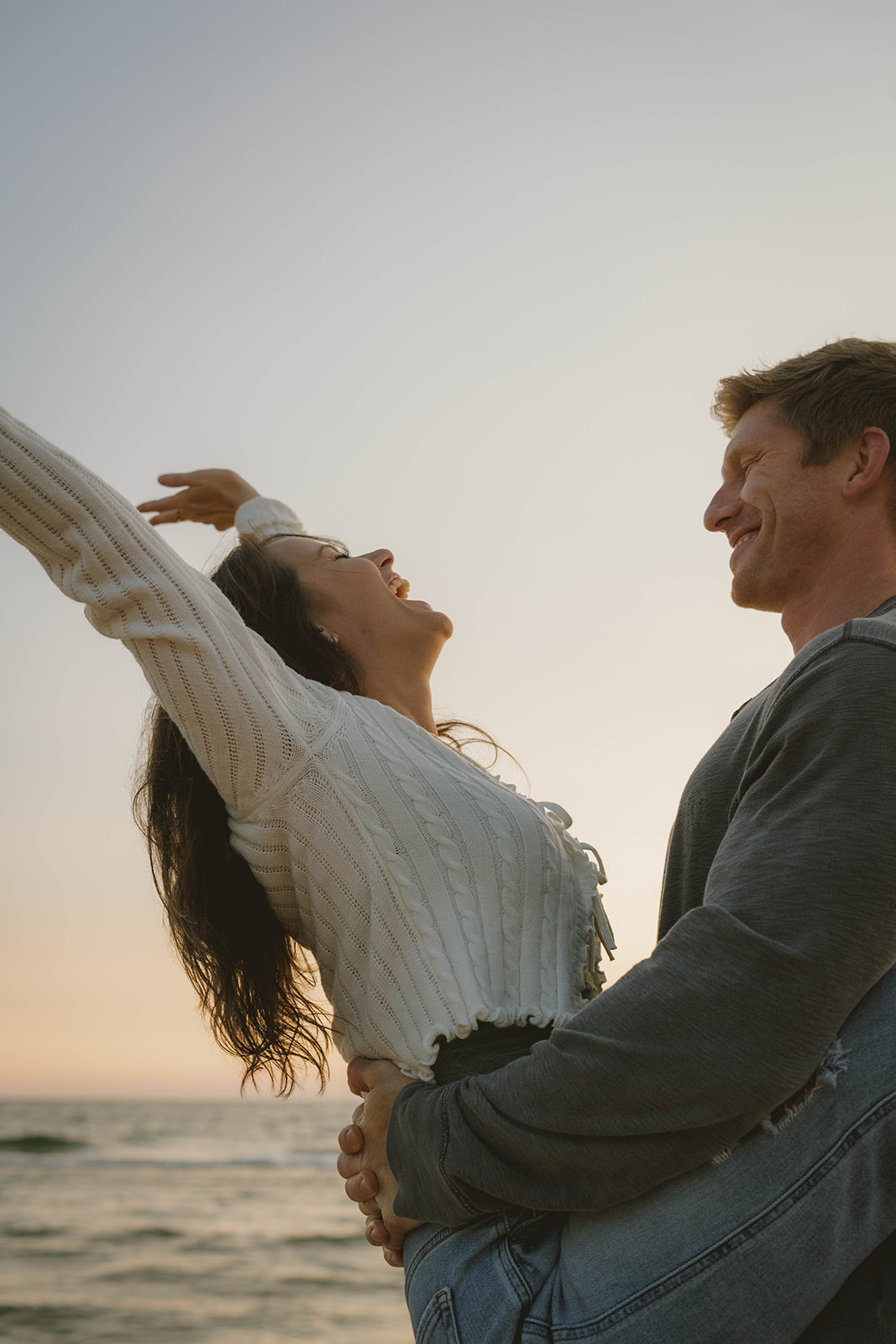 candid photo of a couple laughing, and enjoying their unique beach engagement session