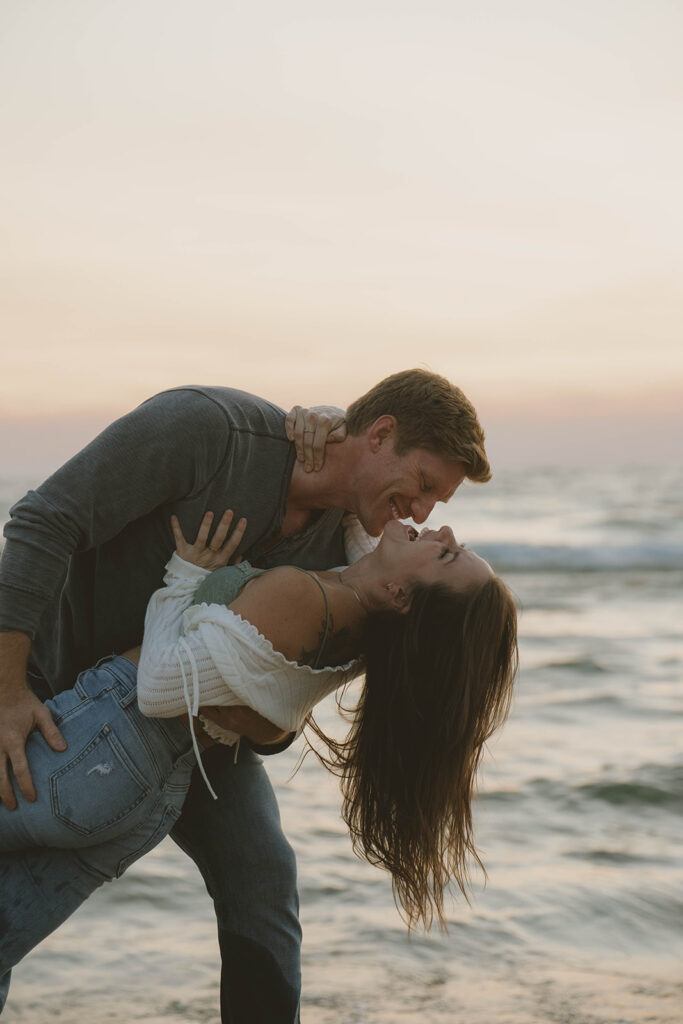 romantic photo captured during a Michigan engagement session with the stunning lake waves in the background