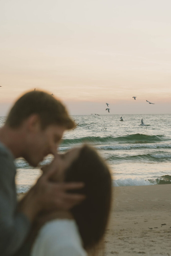 romantic photo captured during a Michigan engagement session with the stunning lake waves in the background