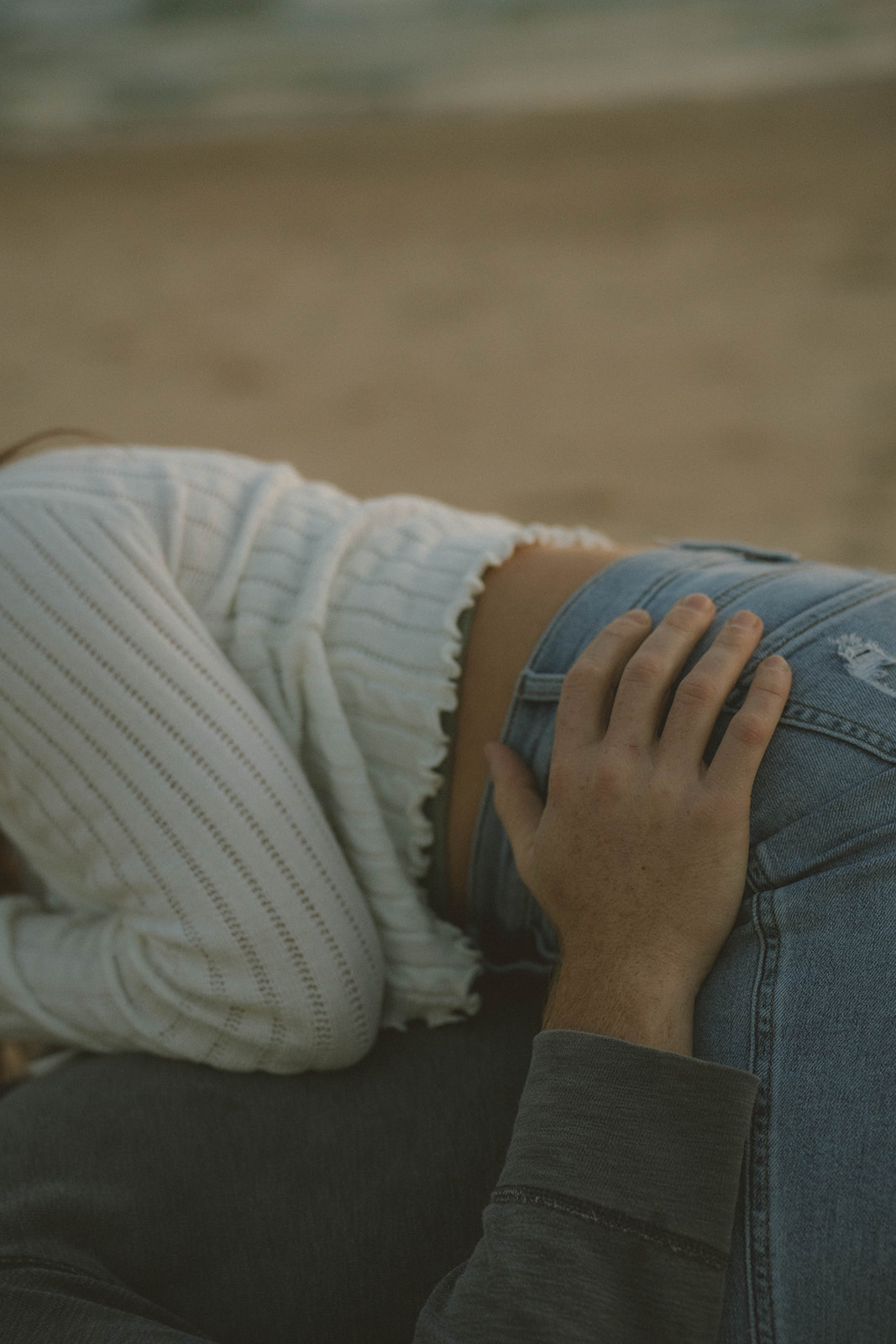 couple share an intimate moment lying on the beach together during their Michigan engagement session