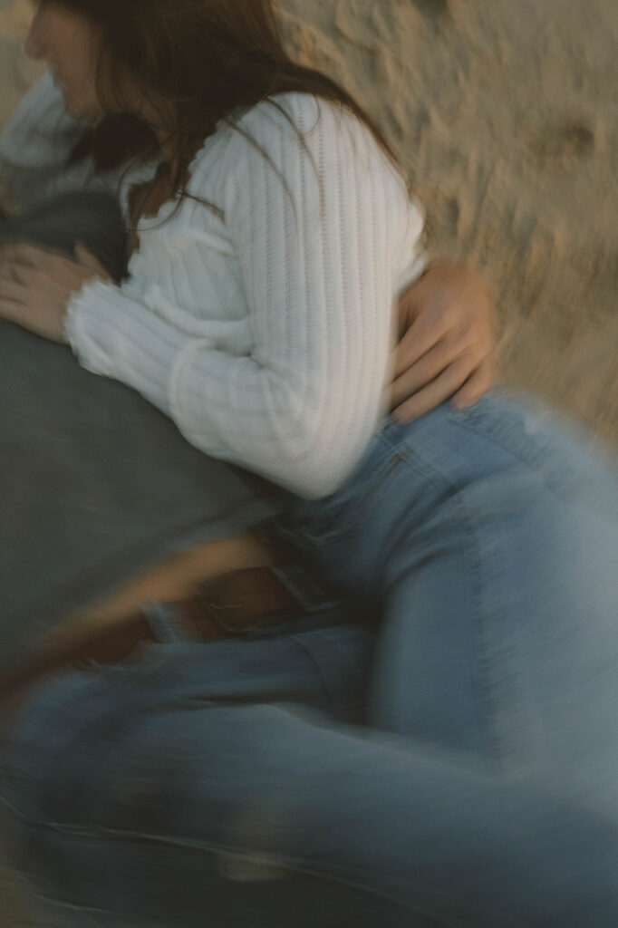 couple share an intimate moment lying on the beach together during their Michigan engagement session