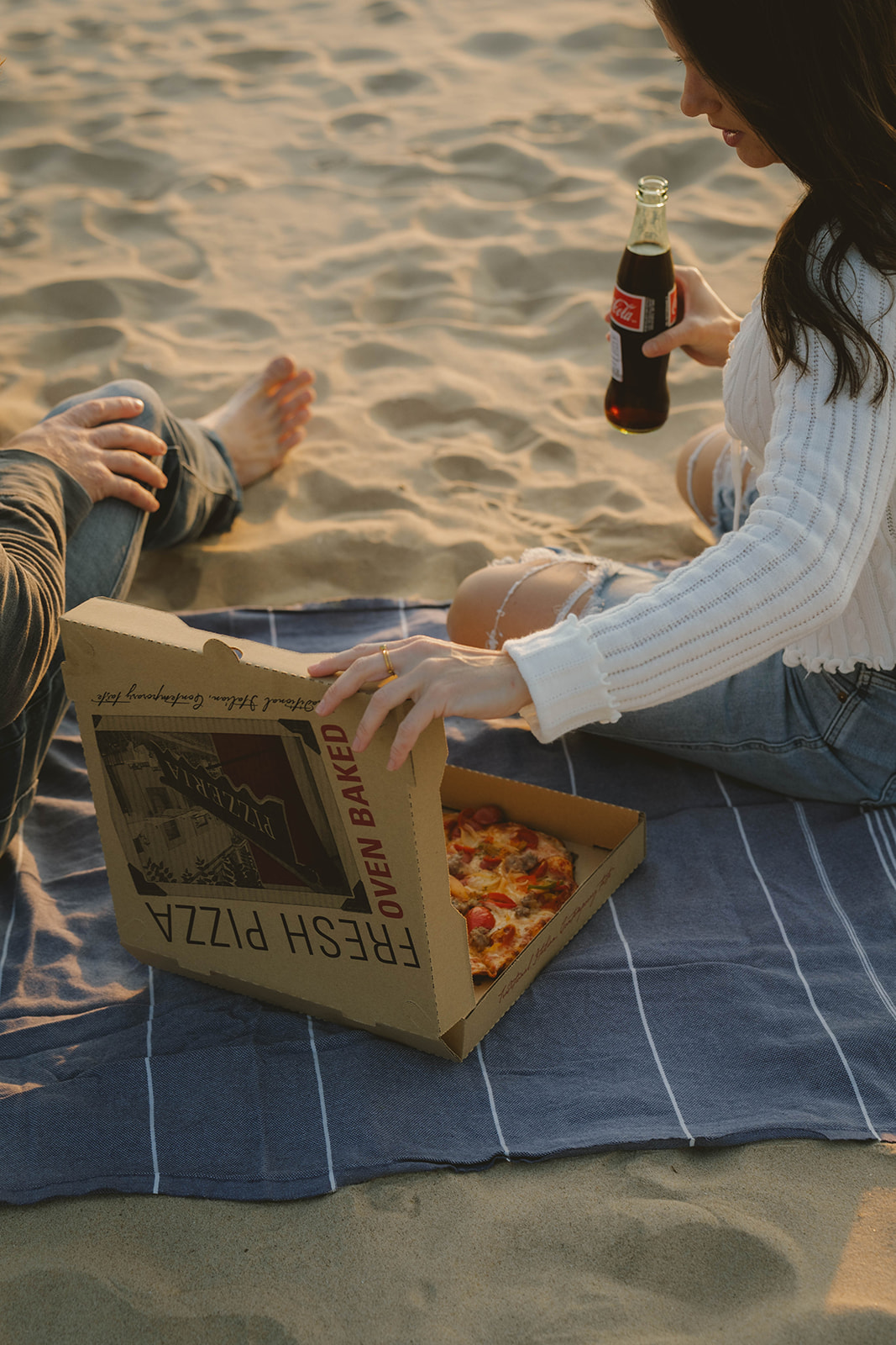 couple share a pizza and coke during their Lake Michigan engagement photos