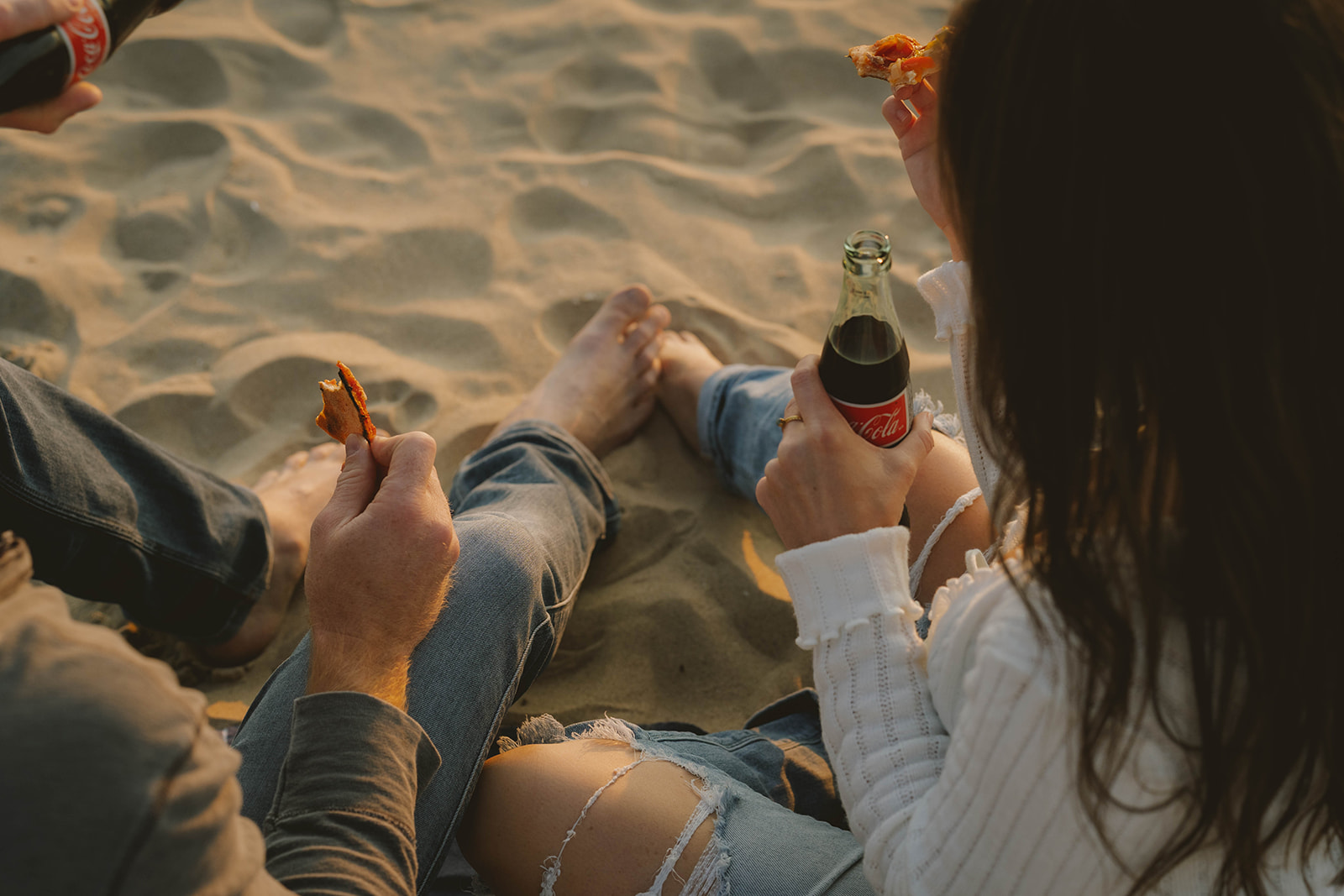 couple share a pizza and coke during their Lake Michigan engagement photos