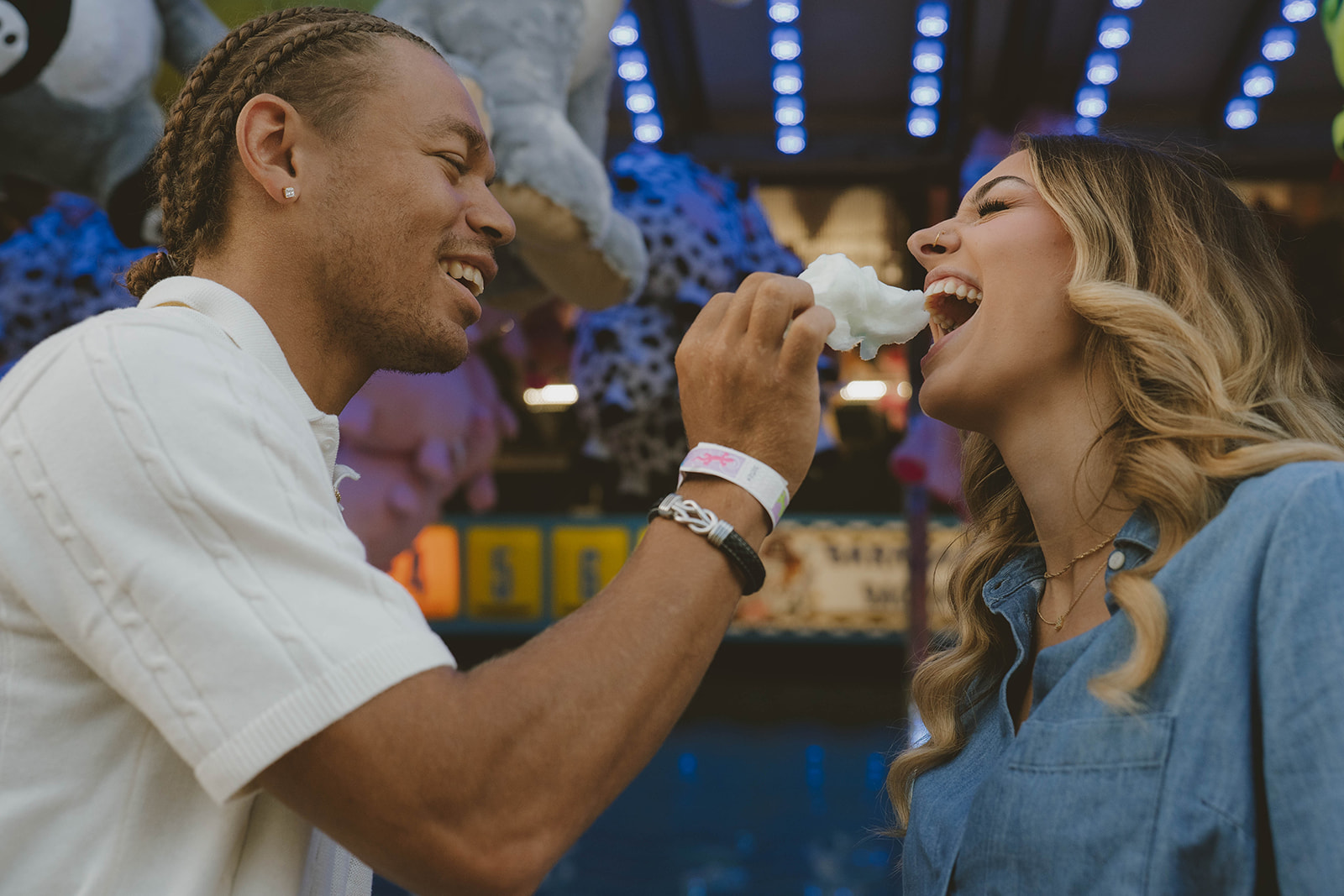 couple share cotton candy during their fun couples photos at the state fair in Michigan