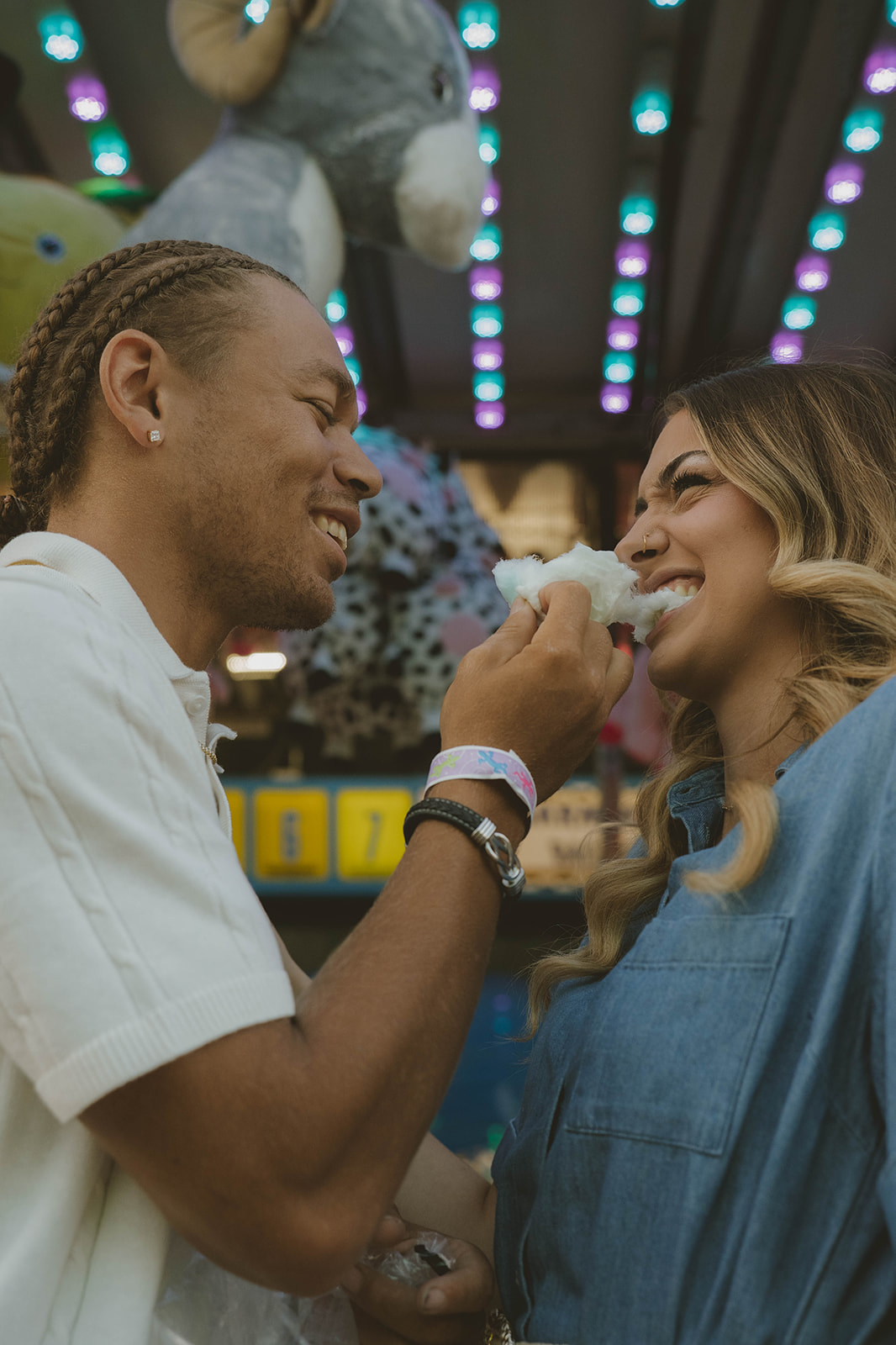 couple share cotton candy during a fun couples photoshoot at the fair