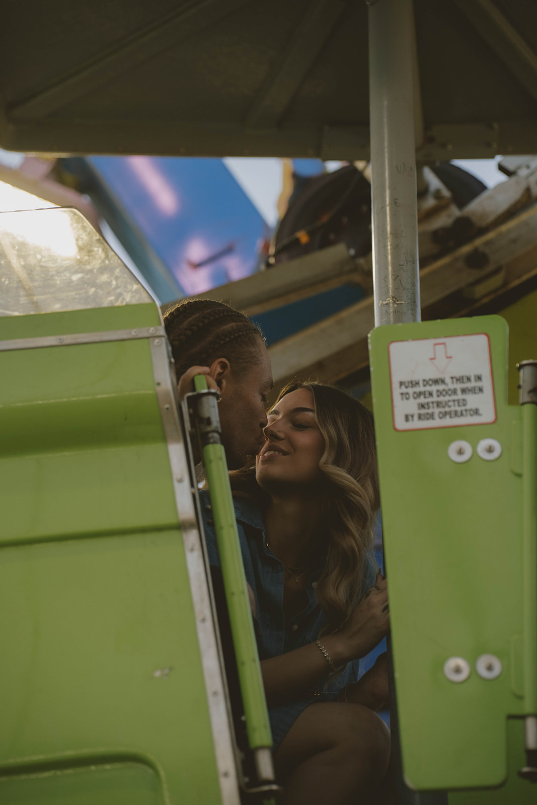 couple share an intimate moment in the ferris wheel seat during fun couples photos at the fair