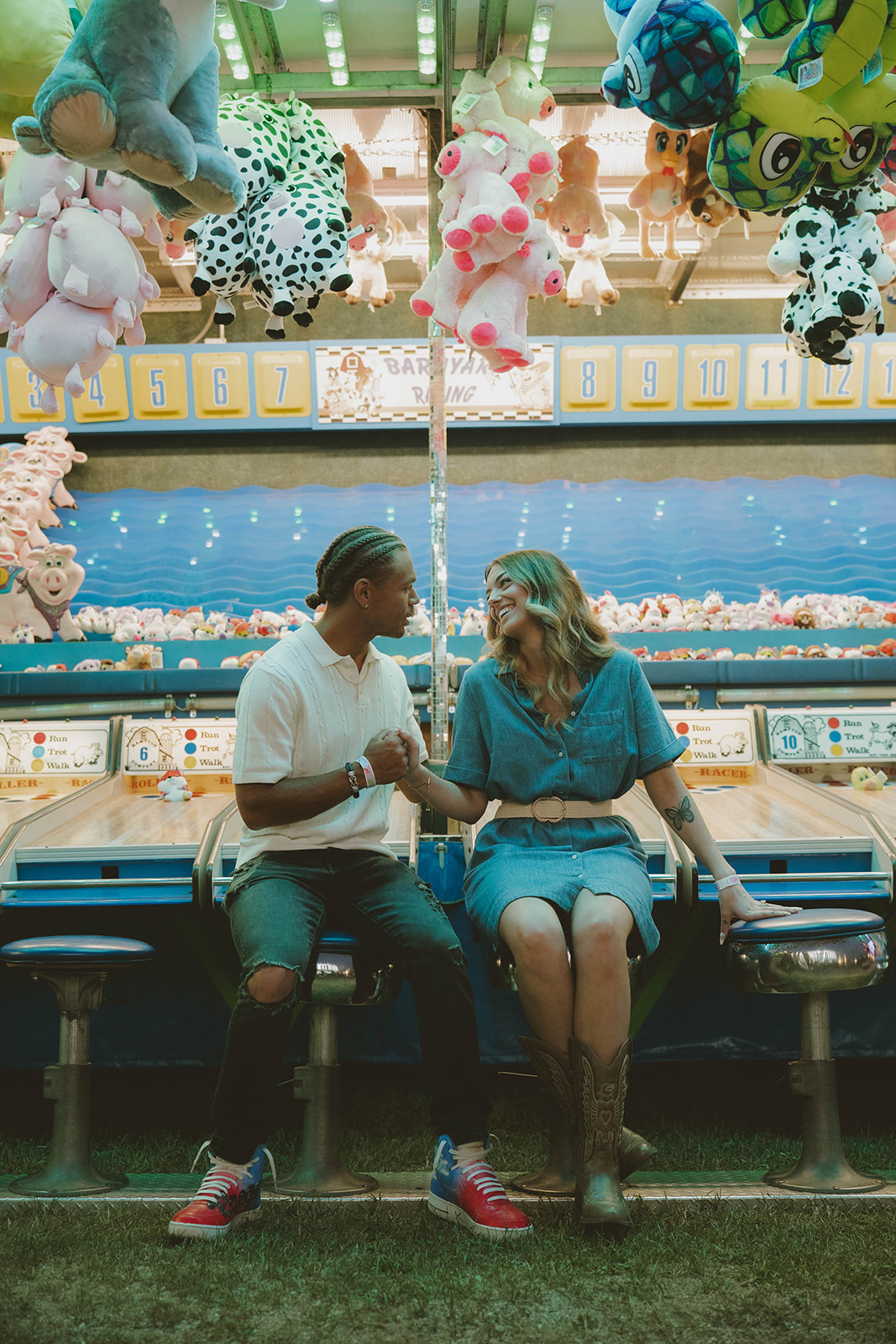 couple sit on the bar stools in front of the skeeball game and share a soft smile at each other