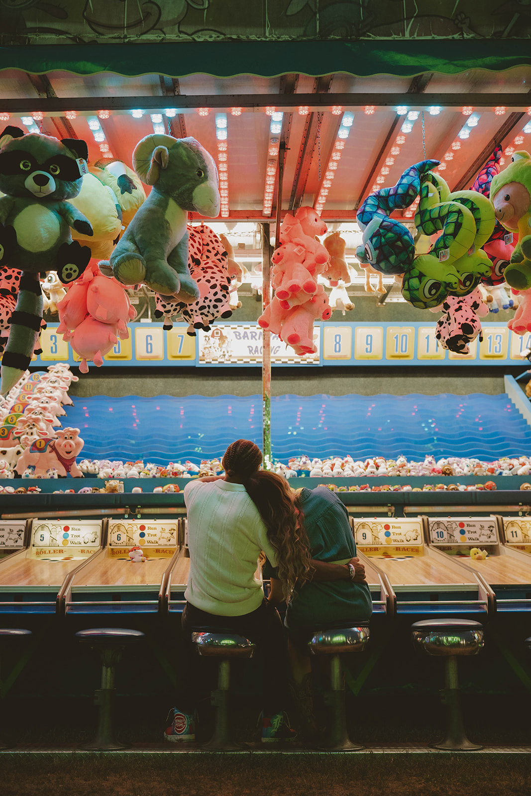 couple embrace and share a side hug sitting on the skeeball stools