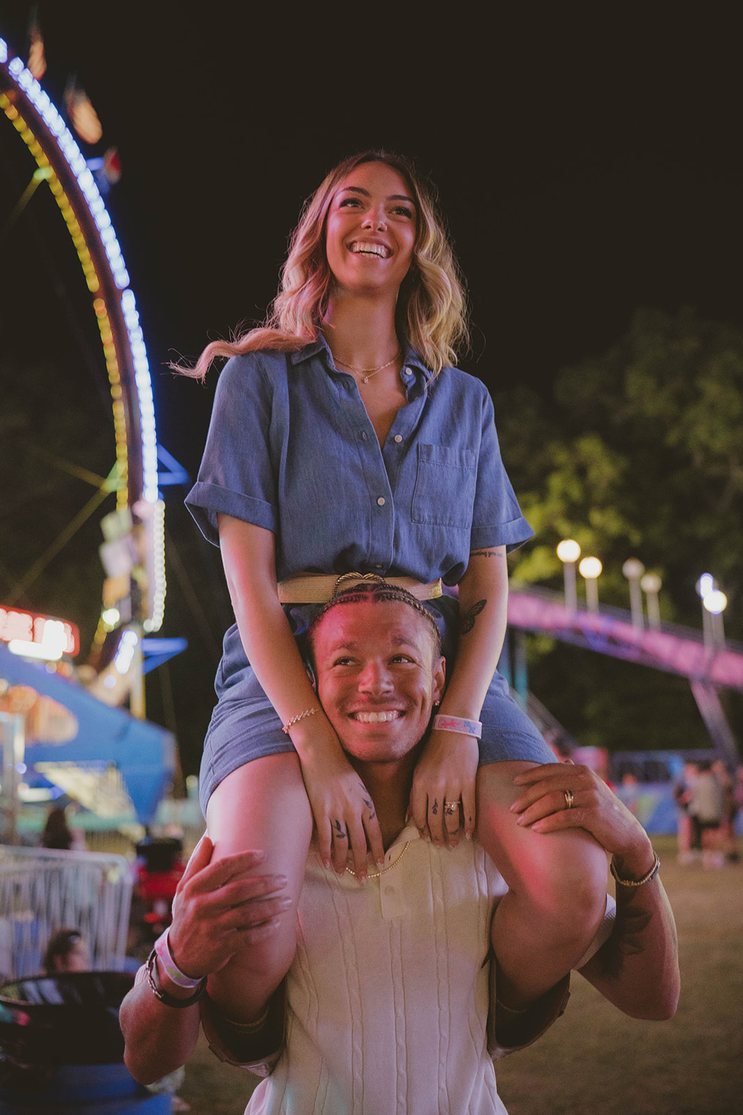 boyfriend gives his girlfriend a ride on his shoulders through the state fair