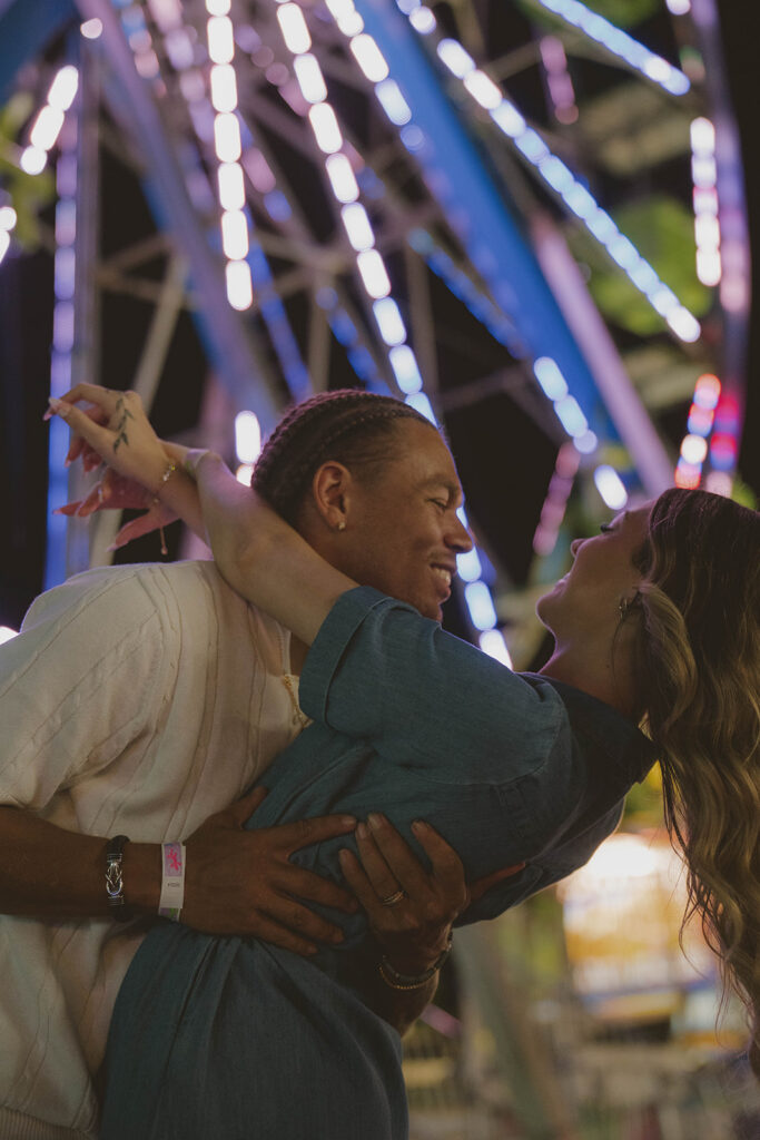 couple share an intimate moment as the ferris wheel lights them up