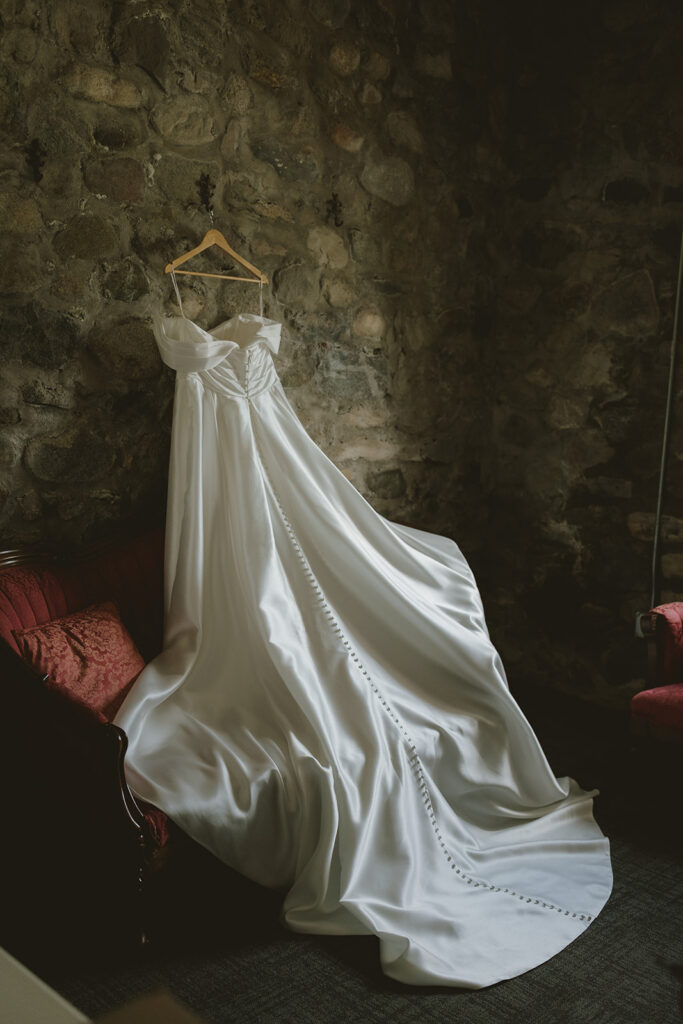 brides dress hangs against the rock wall of Castle Farms a top northern michigan wedding venue!