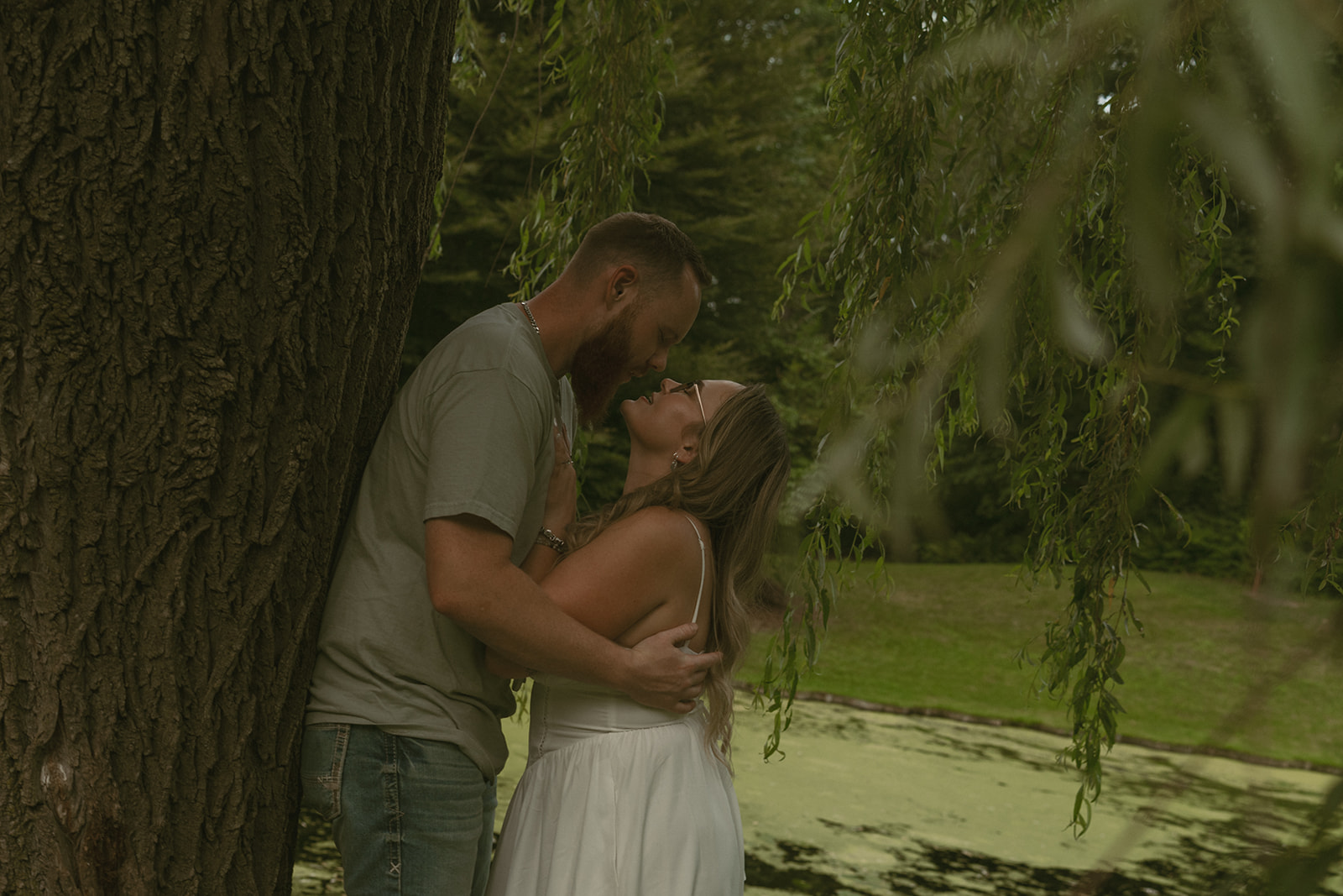 couple lean against a tree sharing intimate moments during their dow gardens engagement photos 