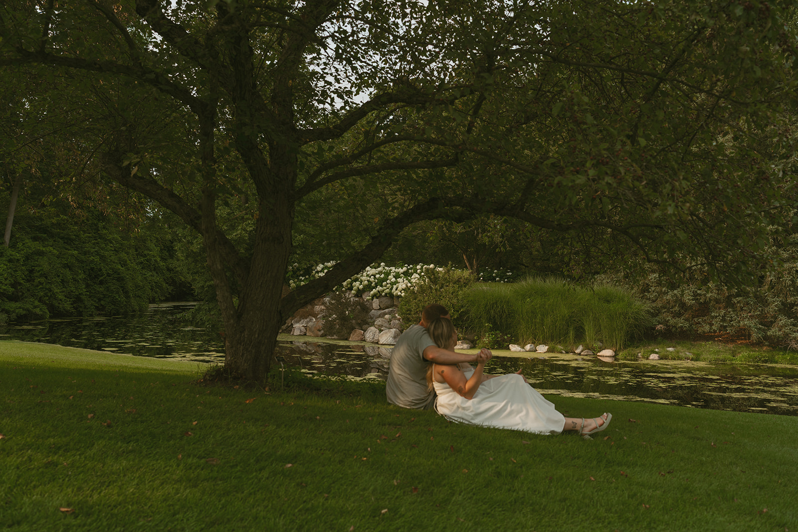 couple sit on the grass together during their dow gardens engagement photos